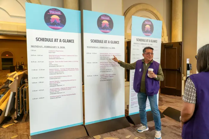 An attendee pointing to a row of Schedule at a Glance signage boards