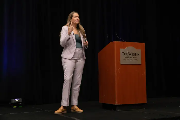 A speaker gesturing at a podium on the main stage