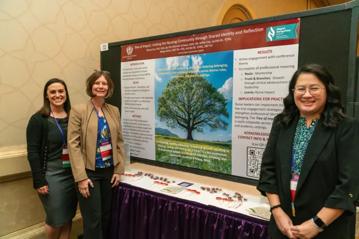 Presenters standing beside a research poster featuring a tree illustration