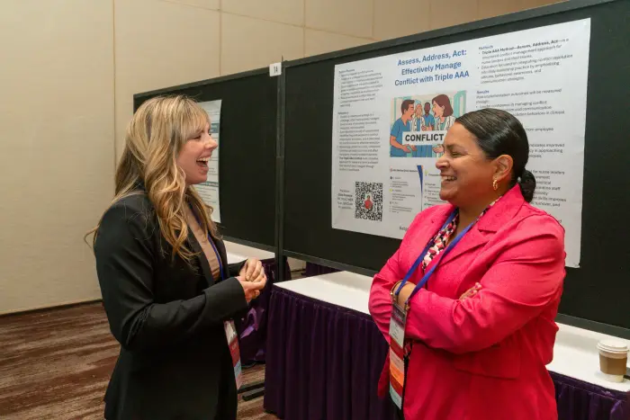 Two attendees in conversation beside the poster-session boards