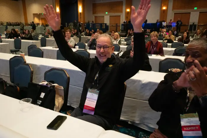 An attendee with both arms raised in celebration during a session