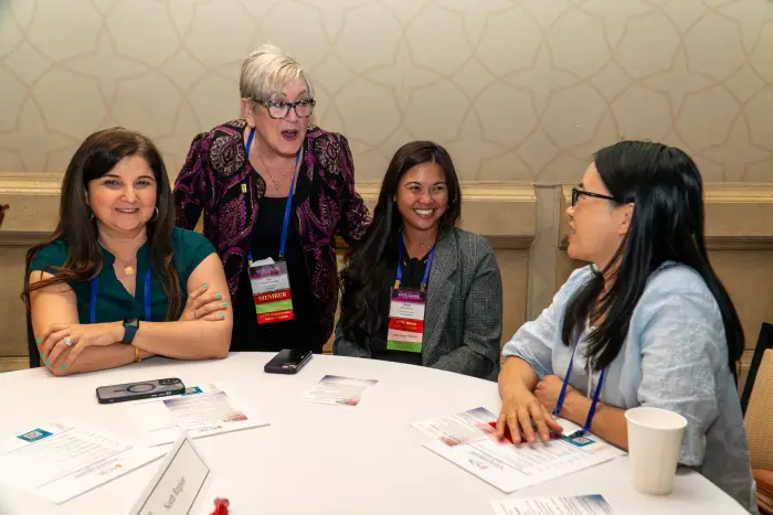 Four attendees talking and laughing around a round table during a networking session