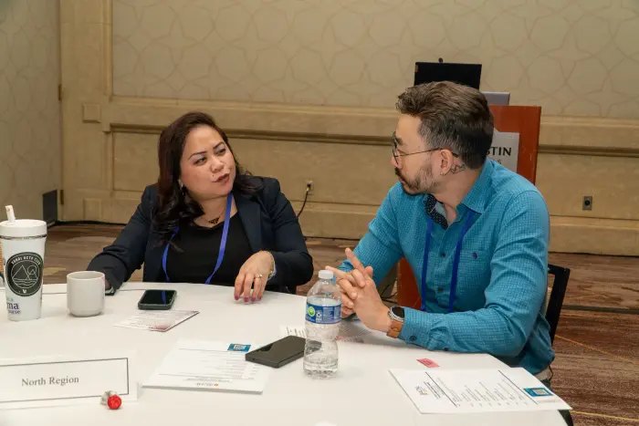 Two attendees in a focused one-on-one discussion at a table