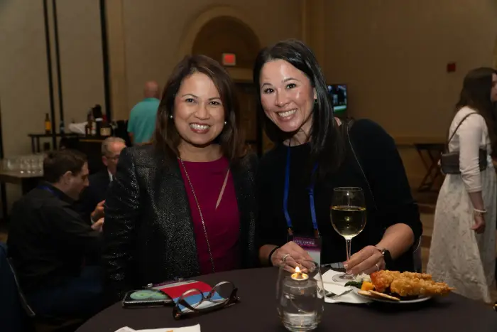 Two attendees smiling together at an evening reception